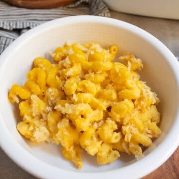 A white bowl contains the curly macaroni pasta cooked in the butternut sauce and a breadcrumb and cheese topping.