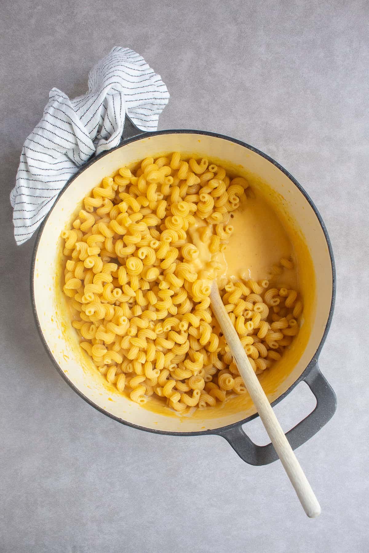The cooked pasta is added to the pot with the golden sauce.