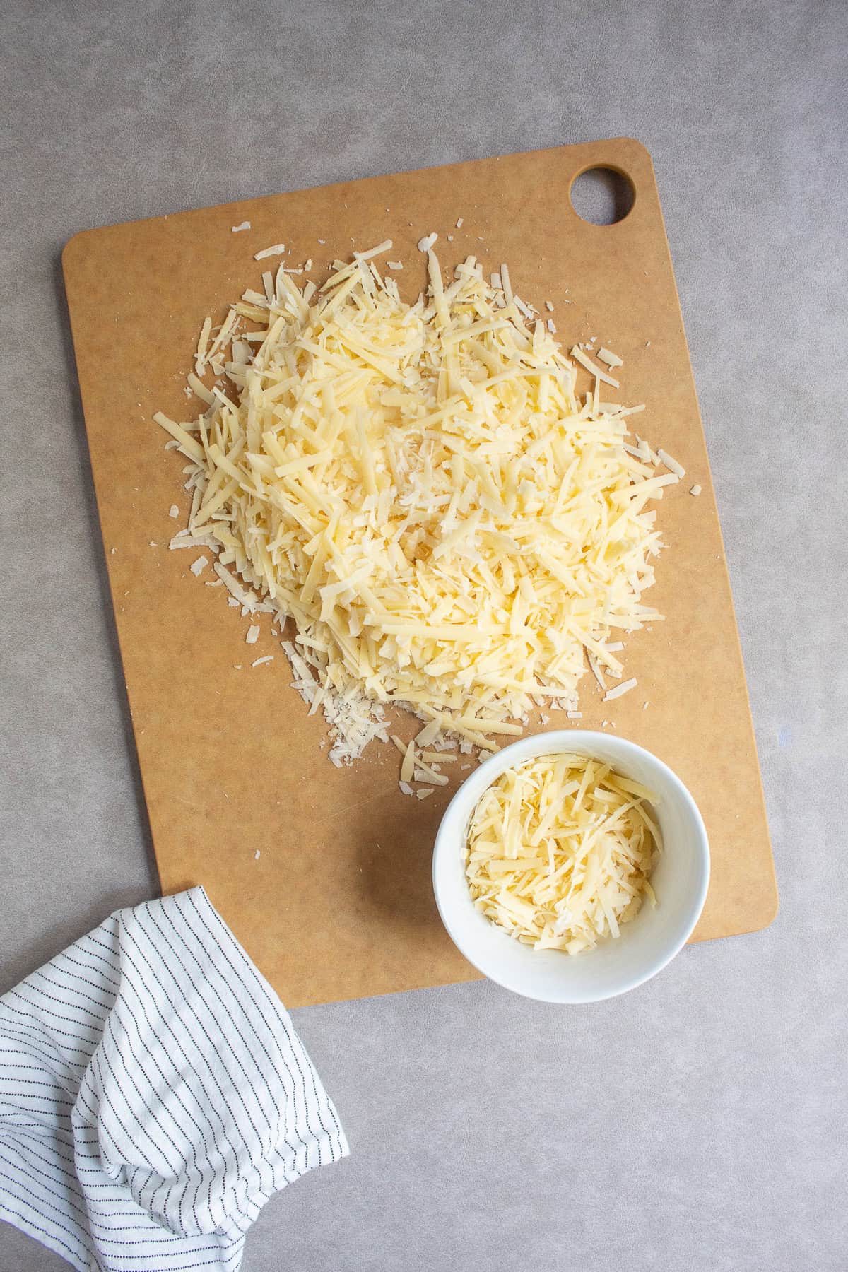 The two shredded cheese are combined and a portion is set aside in a small white bowl.