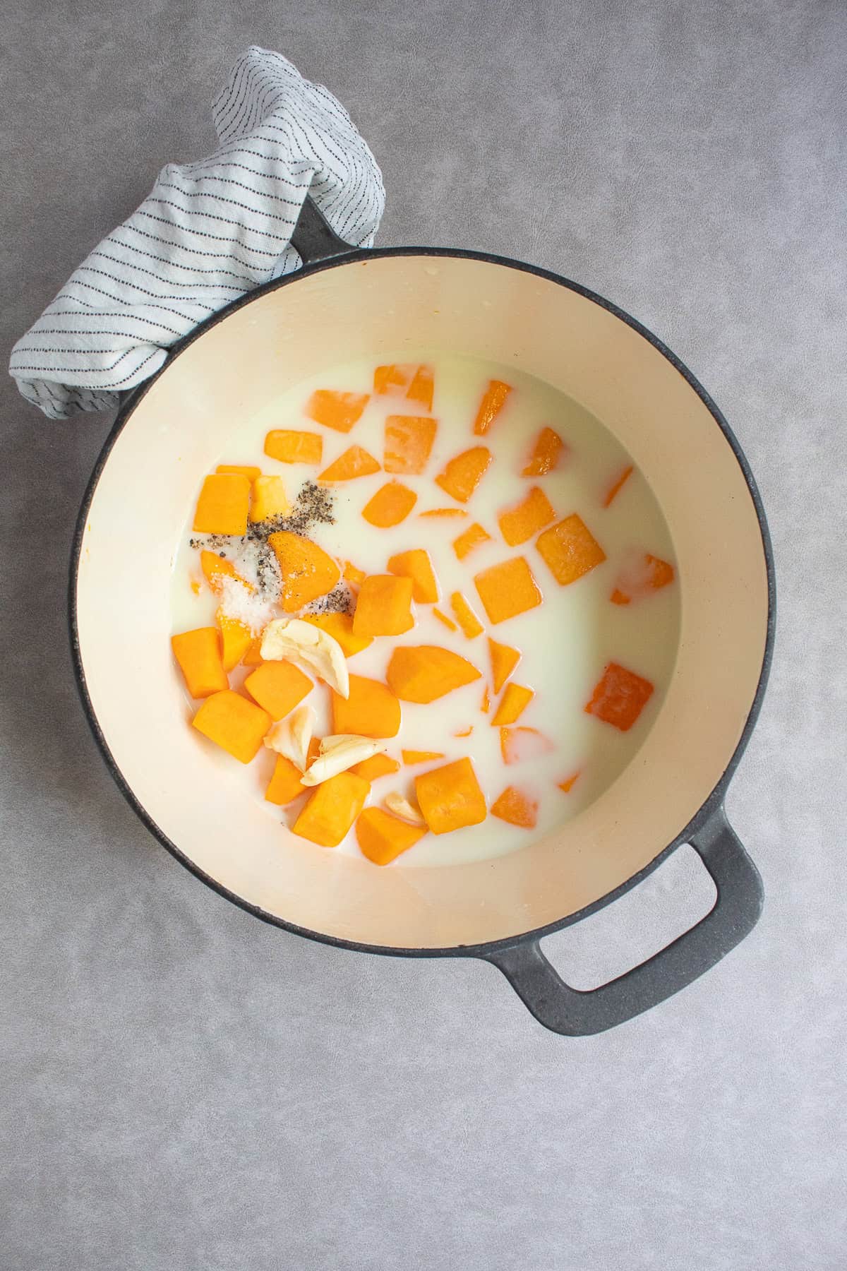 The squash and garlic are added to a large pot with milk and broth.
