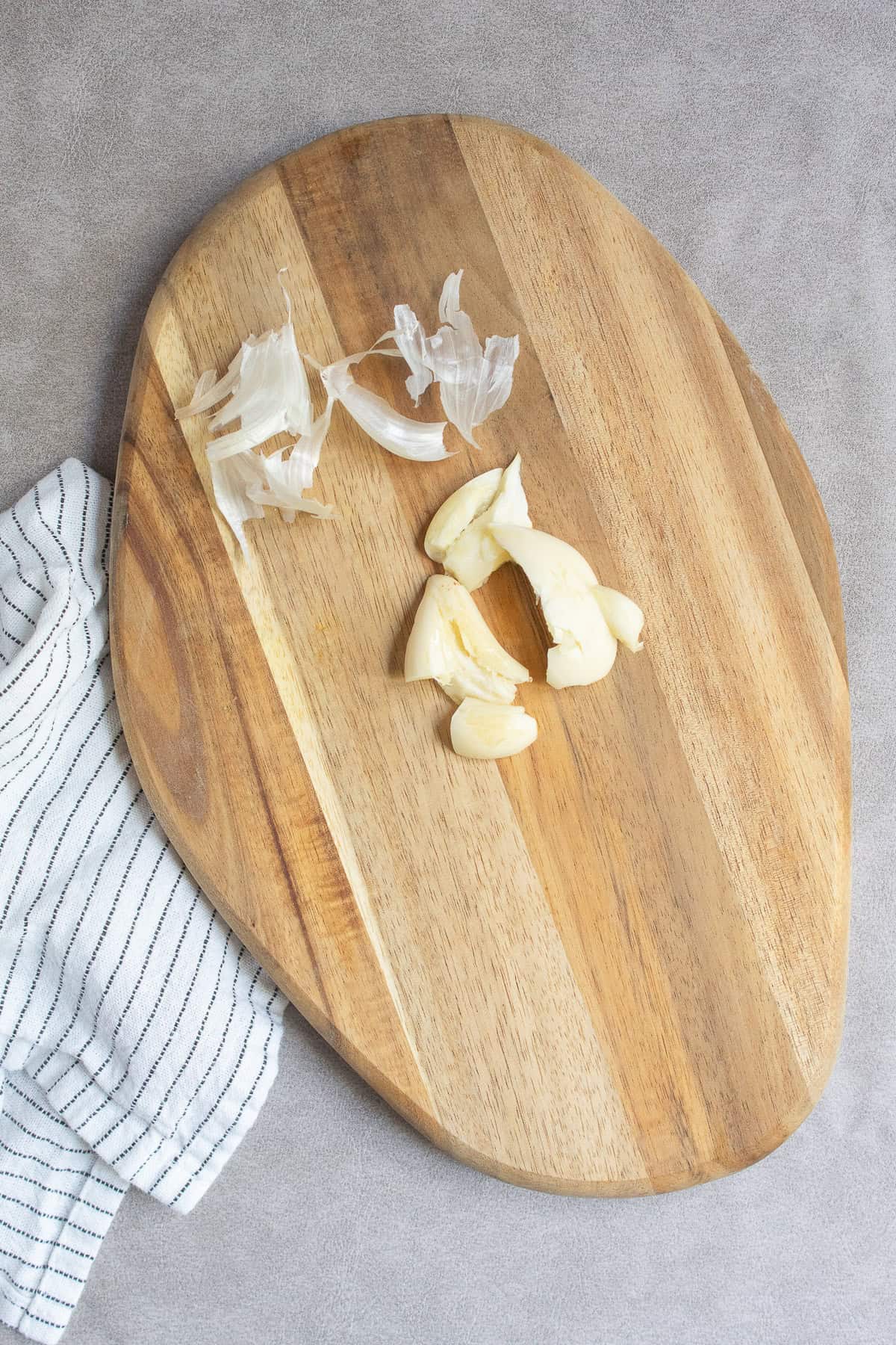 The garlic cloves are peeled and crushed in a wood cutting board.