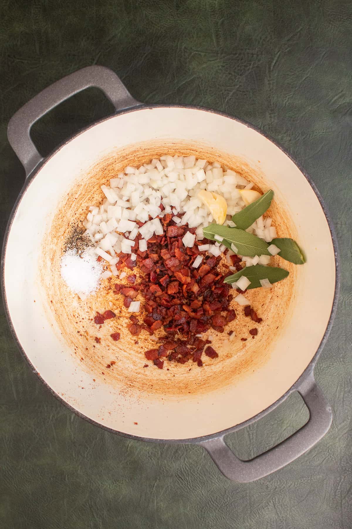 Cooked bacon, chopped onion, garlic, and sage are added to a soup pot.