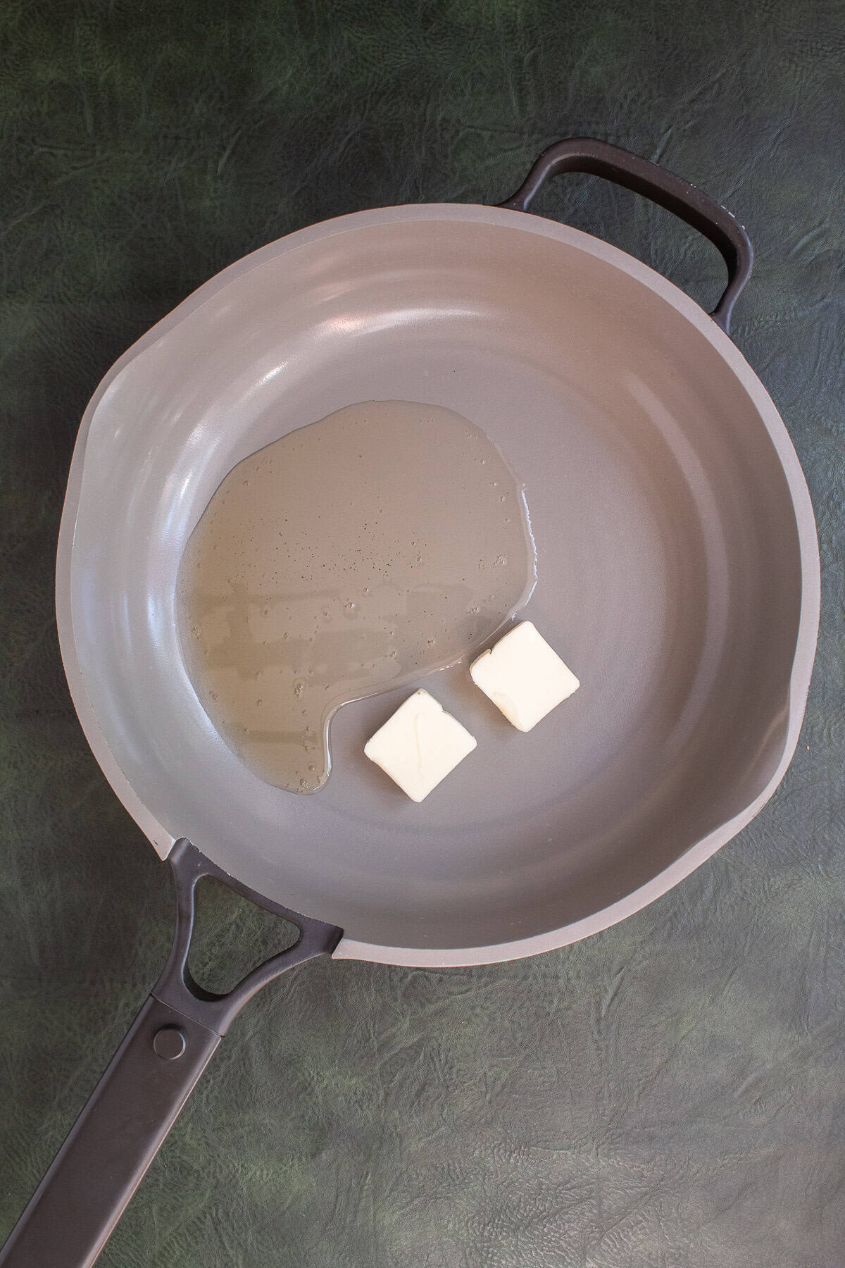 Butter and bacon grease are added to a light colored skillet.
