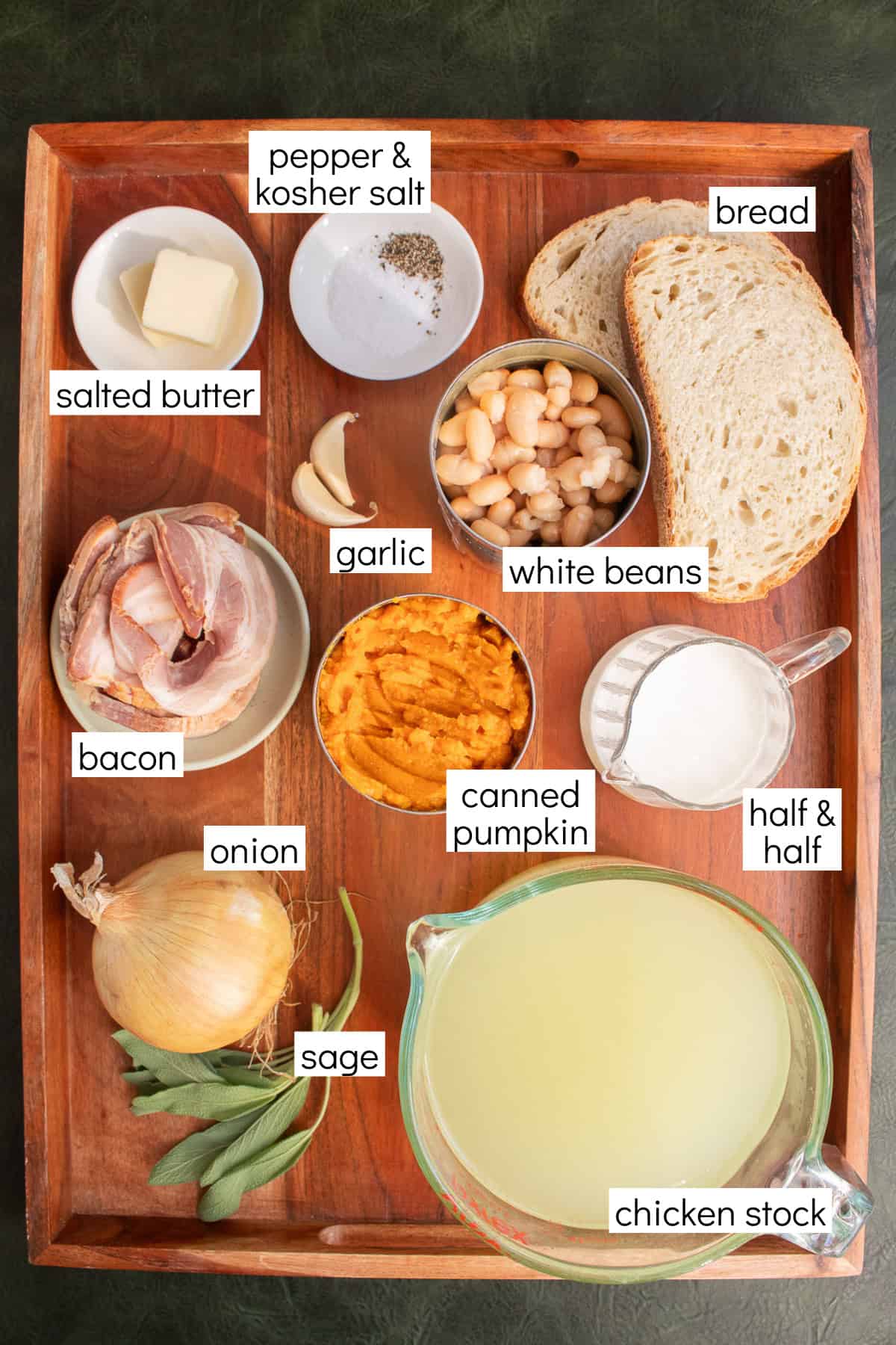 Ingredients for the recipe are displayed and labeled with white text boxes including the words pepper & kosher salt, bread, salted butter, garlic, white beans, bacon, canned pumpkin, half & half, onion, sage, and chicken stock.