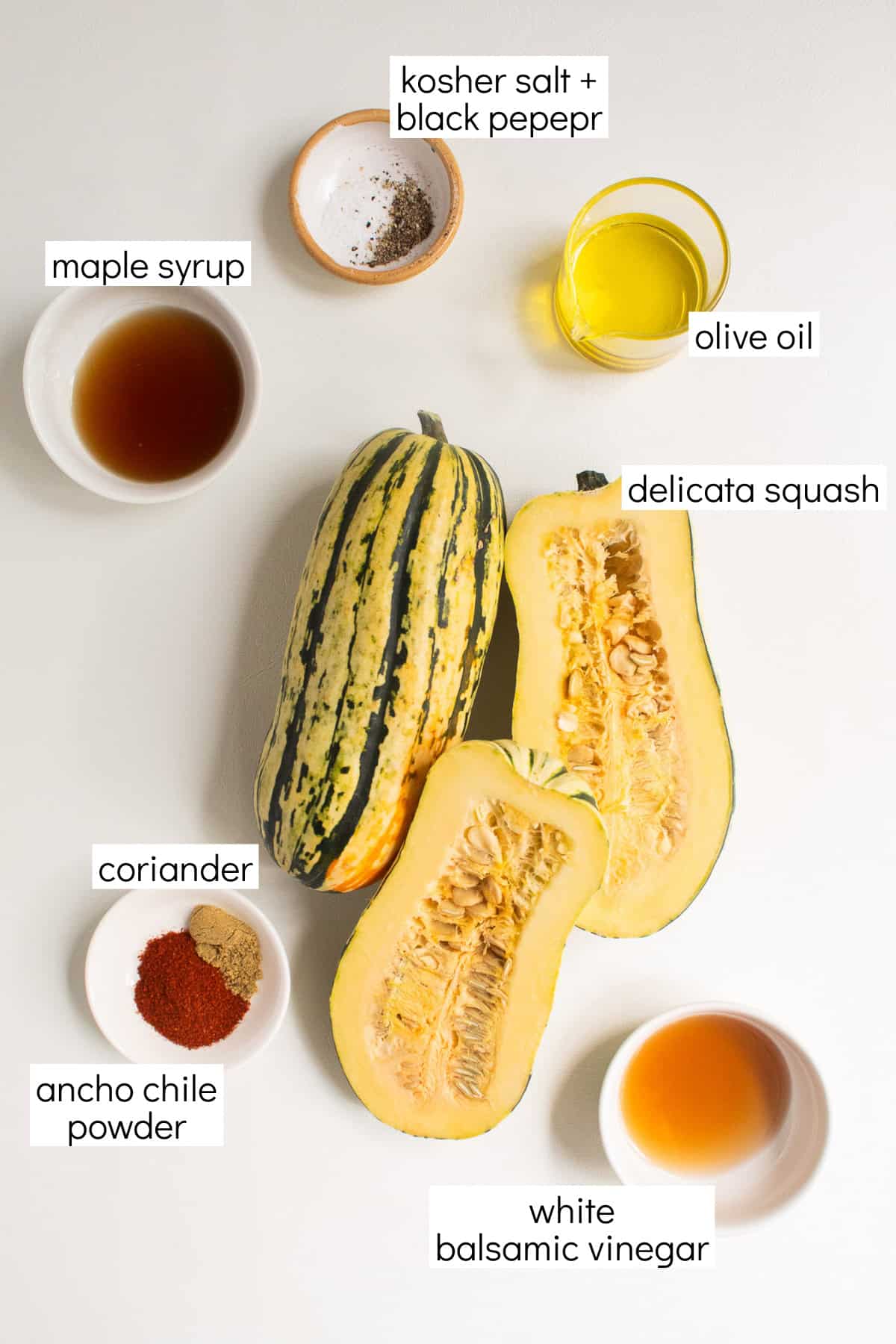 Ingredients for the recipe are displayed and labeled with white text boxes including the words kosher salt + pepper, olive oil, maple syrup, delicata squash, coriander, ancho chile powder, and white balsamic vinegar.
